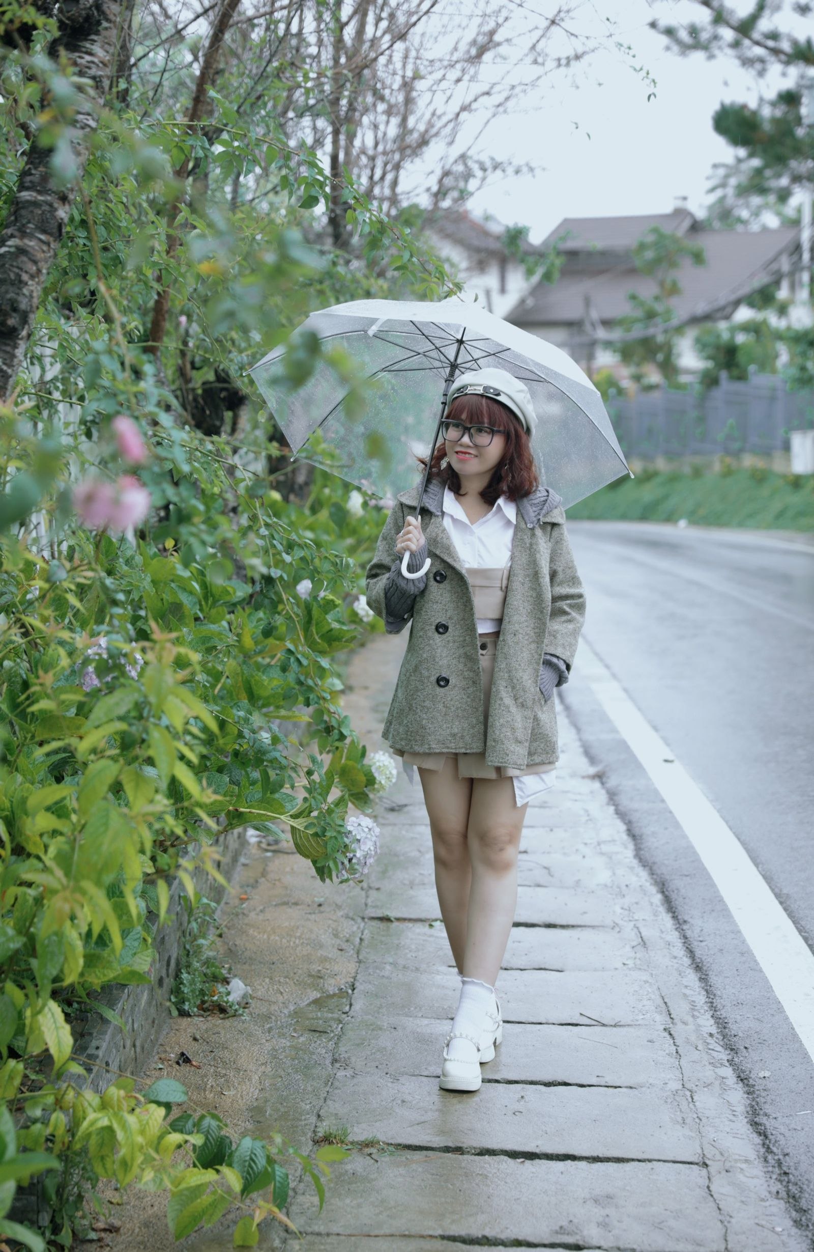 Woman wearing a coat and holding an umbrella on a rainy street