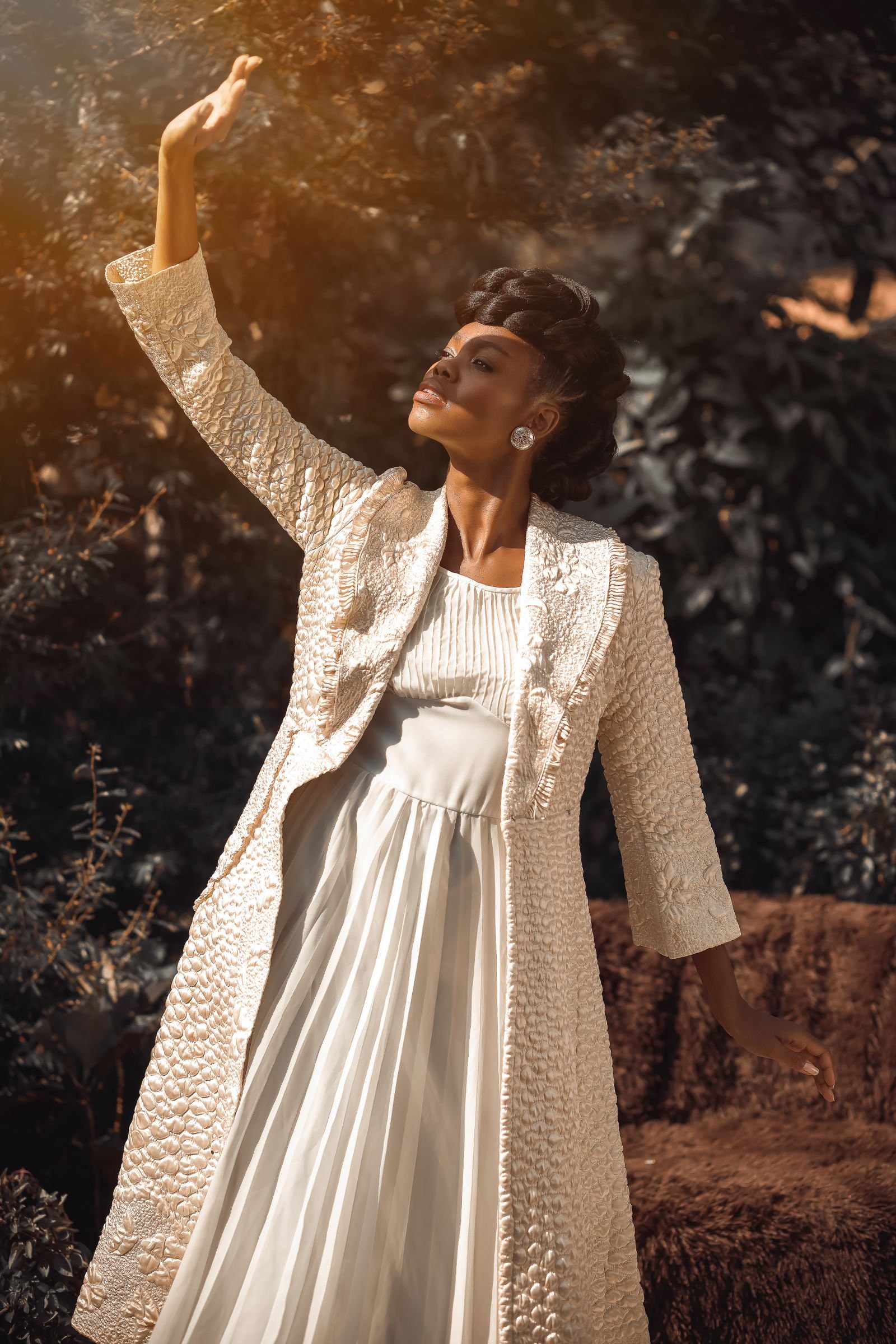 Woman wearing a light-colored dress and textured jacket outdoors
