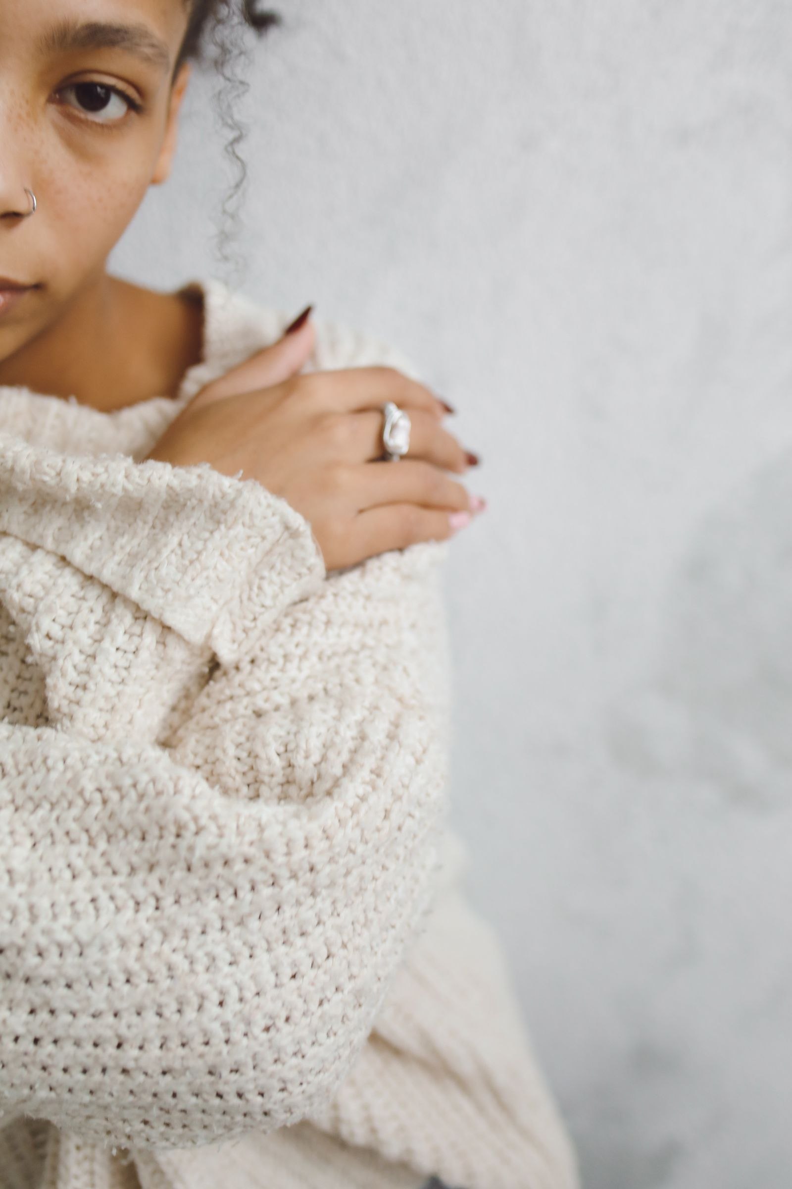 Close-up of a woman wearing a knitted sweater with her hand near her chest