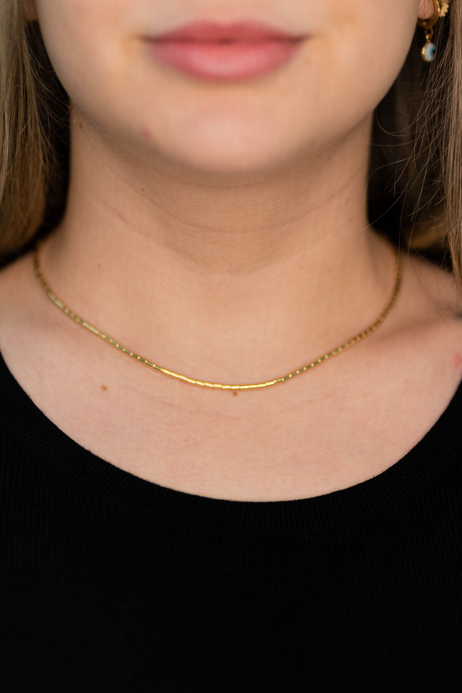Close-up of a gold necklace worn with a black top