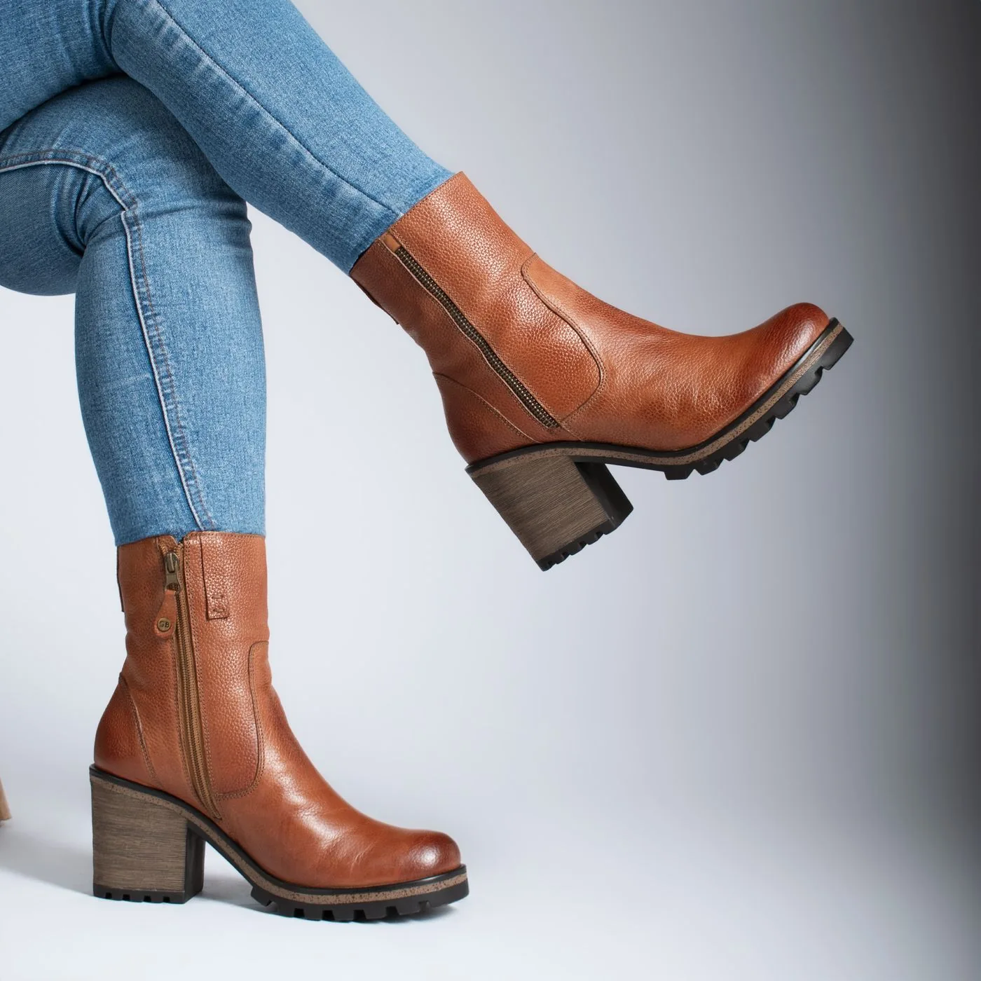 Brown ankle boots with visible block heels beneath blue jeans.