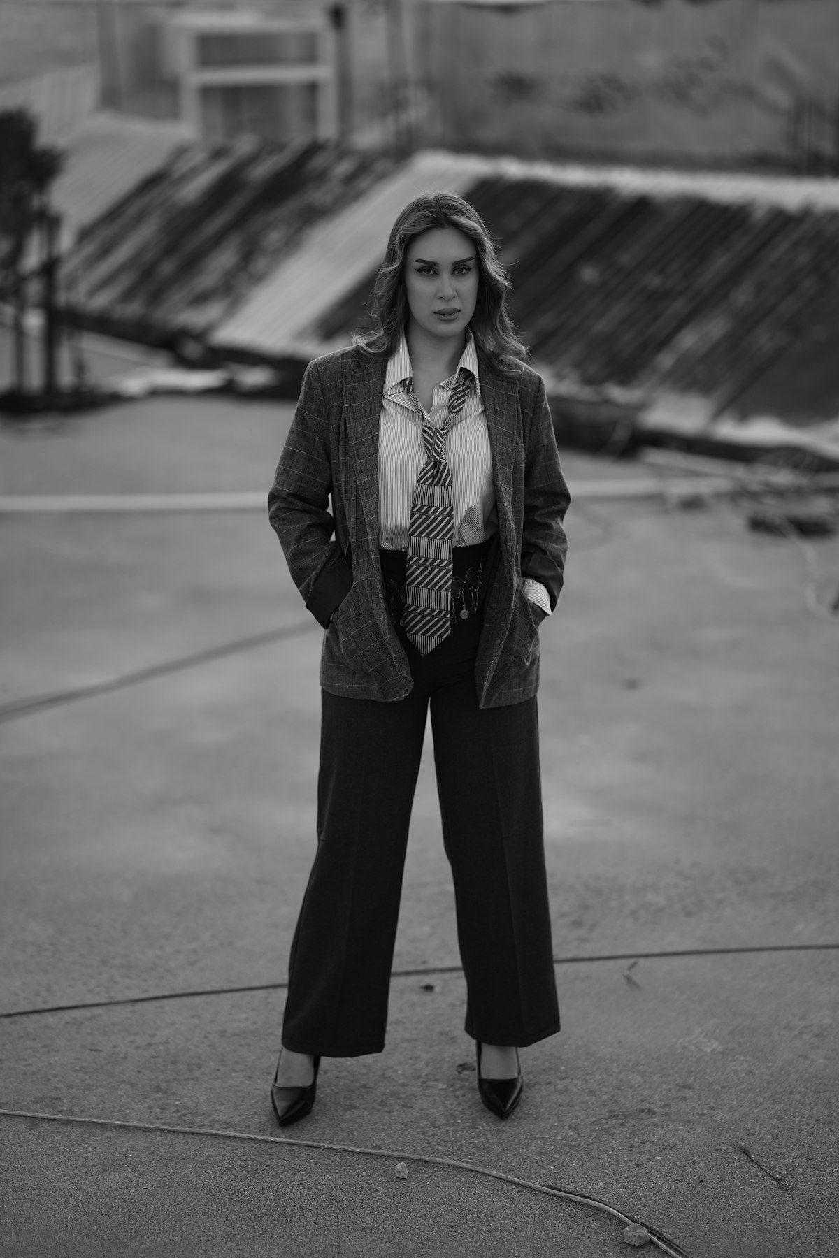 A monochrome view of a woman in a jacket and wide trousers outdoors.