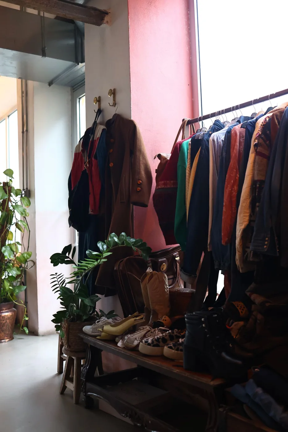 Coats and other garments displayed on a rail beside a bright shop window.