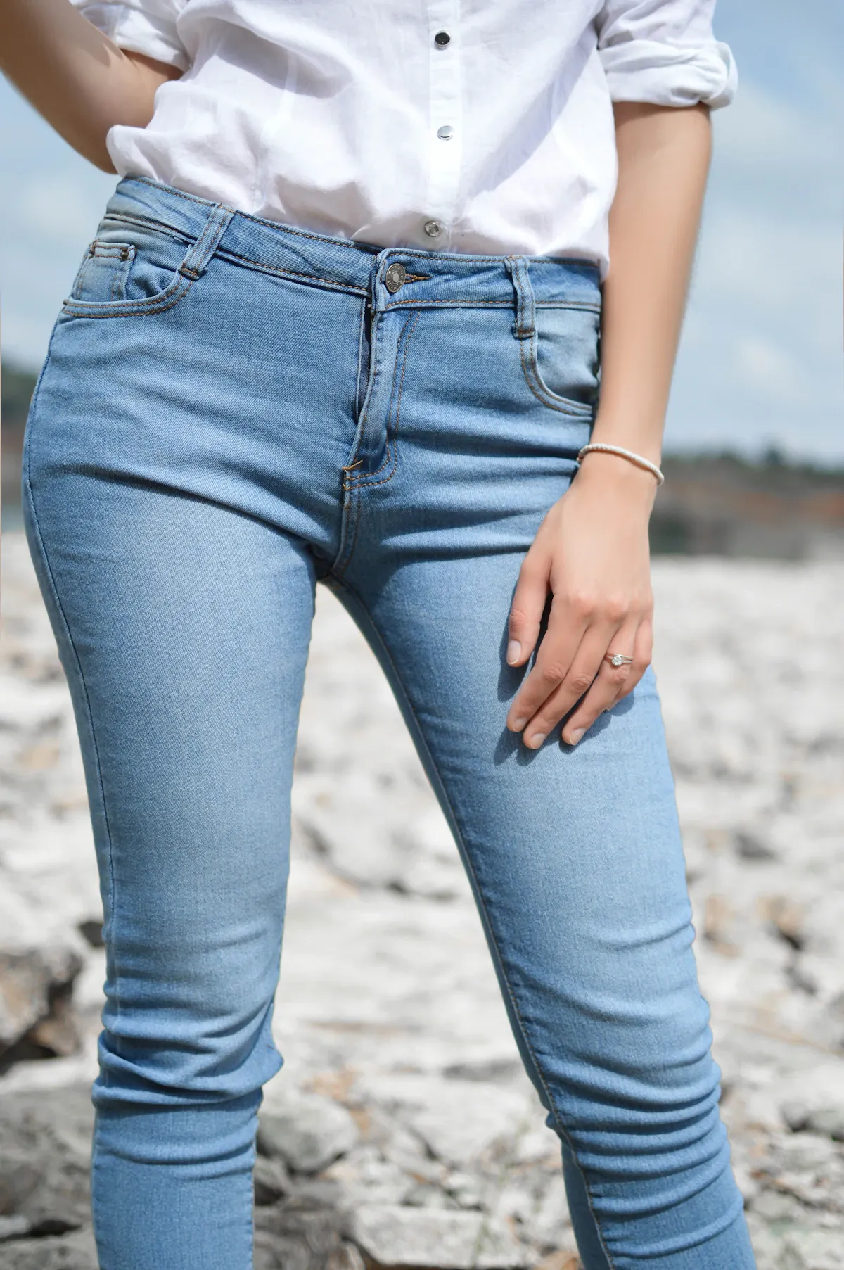 A white shirt tucked into pale blue jeans outdoors.