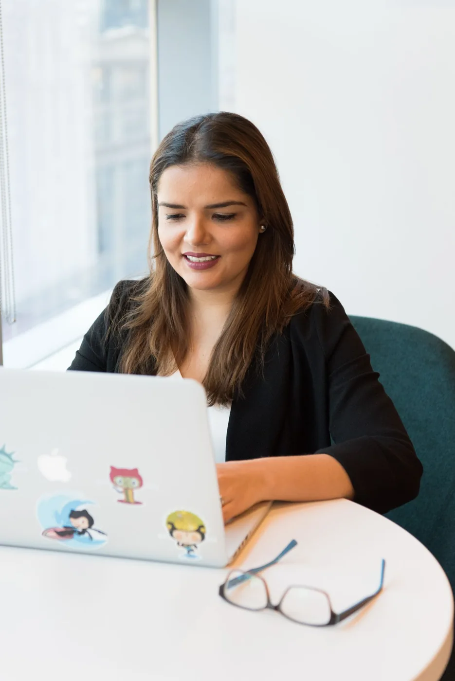 A woman wearing a dark blazer while using a laptop at a table.