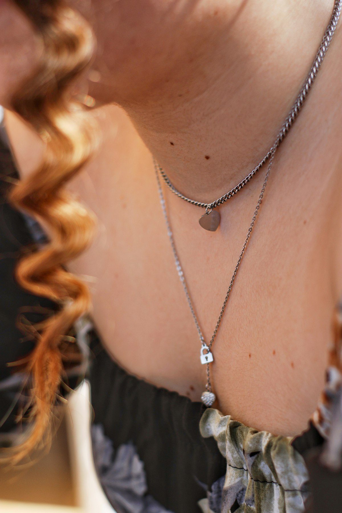 Several necklaces visible above a floral neckline.