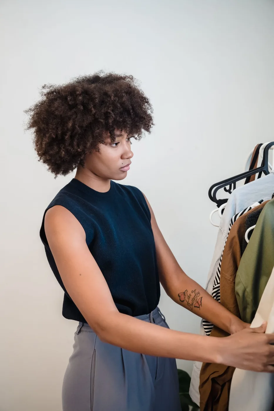 A woman looking through garments on a clothing rail.