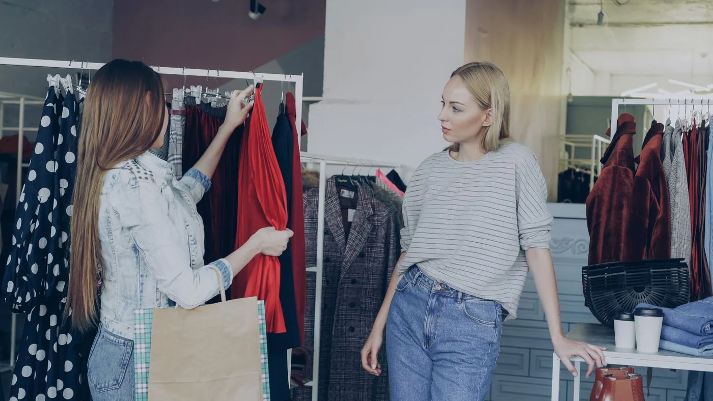 Two women looking at clothes on a shop rail.