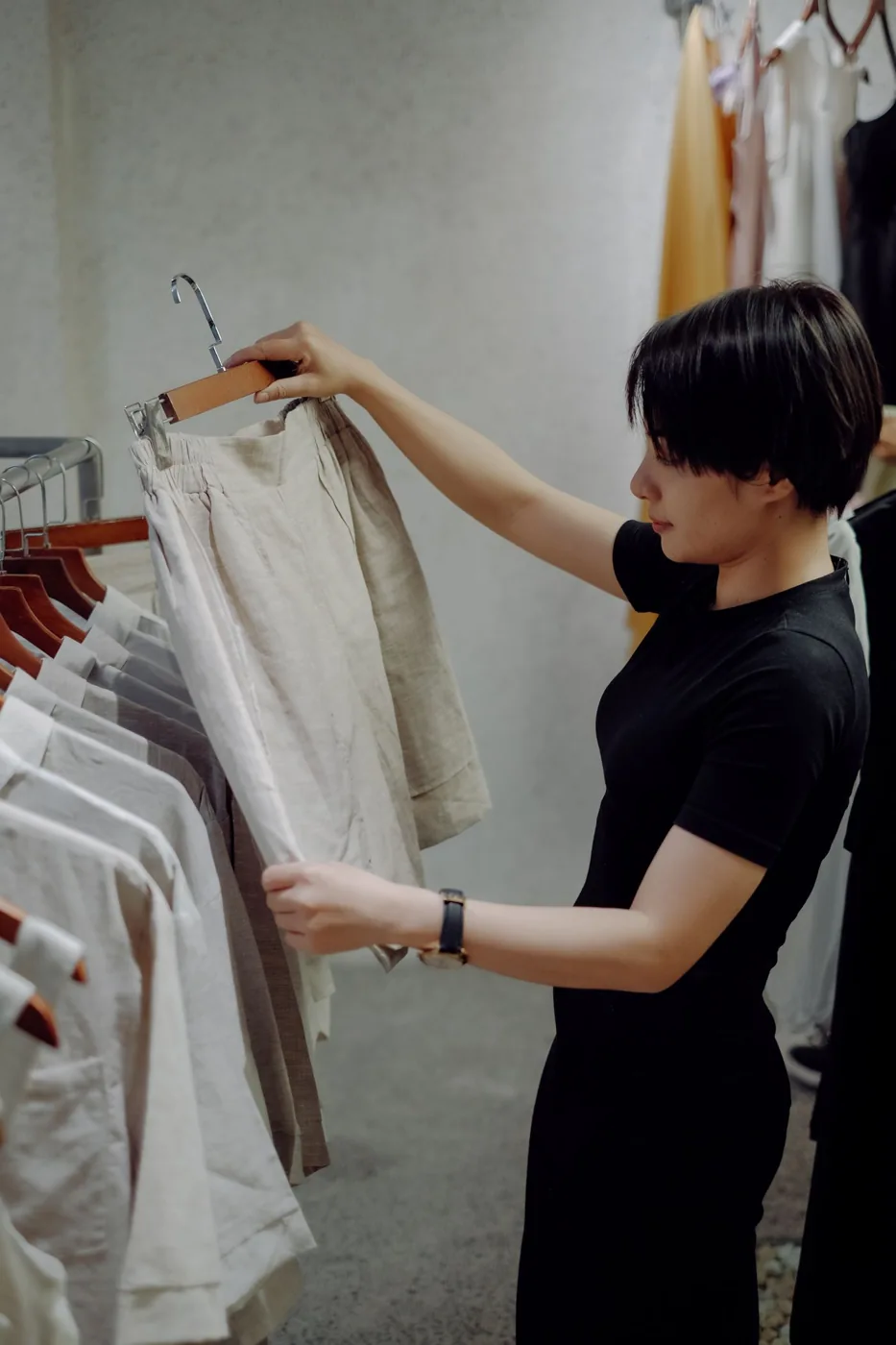 A woman examining pale shorts on a hanger in a clothing shop.