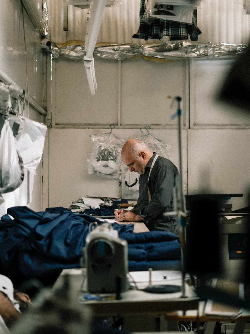 Tailor sewing a garment in a fabric-filled workshop